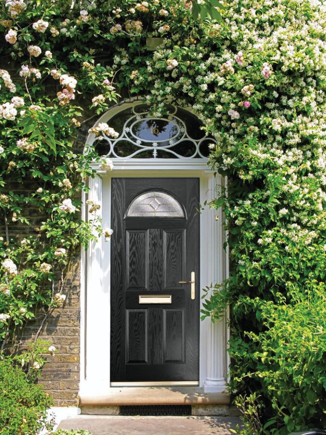black composite front door, surrounded by an arch of flowers