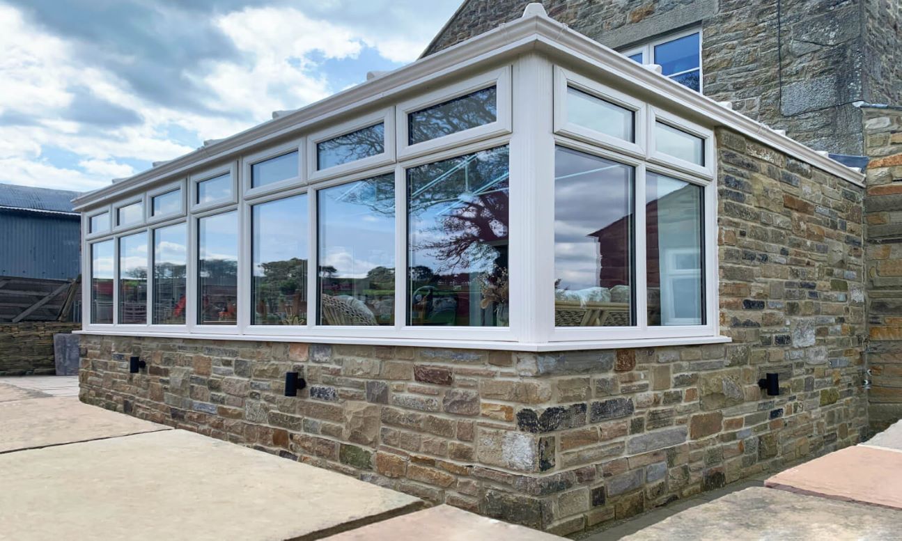 close up of white upvc conservatory with brickwork